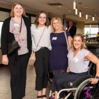 4 women at event pose for a photo by the bar